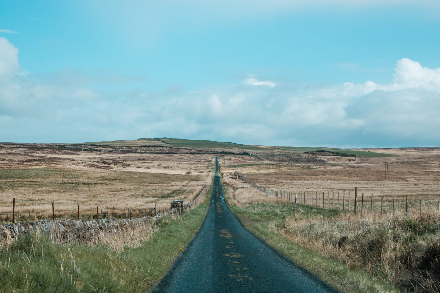 Mittendurch die Landschaft führt eine lange, schnurgerade, schmale Straße