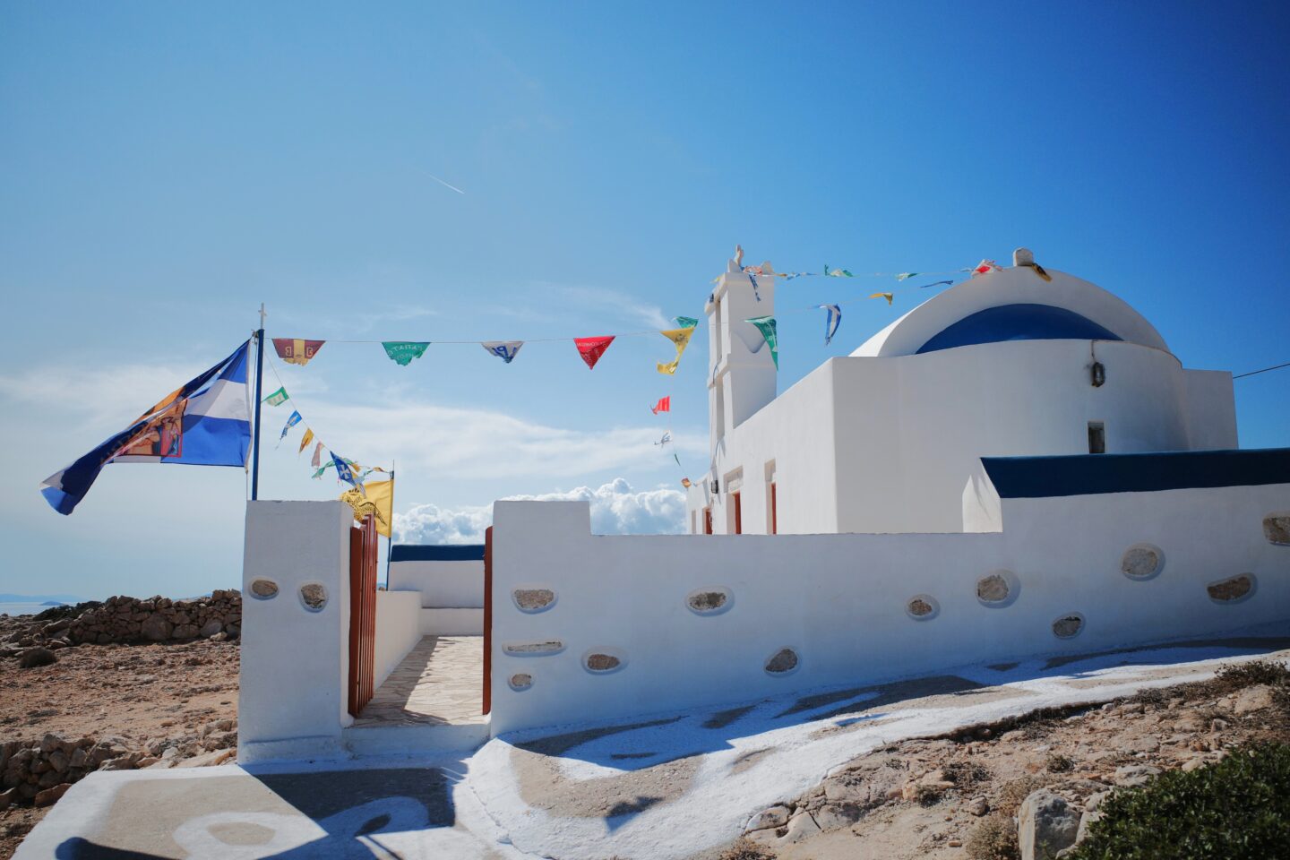 Inselhopping auf griechische Inseln. Das Bild zeigt eine kleine festlich geschmückte Kirche im typischen Kykladenstil vor einem Panigiri.