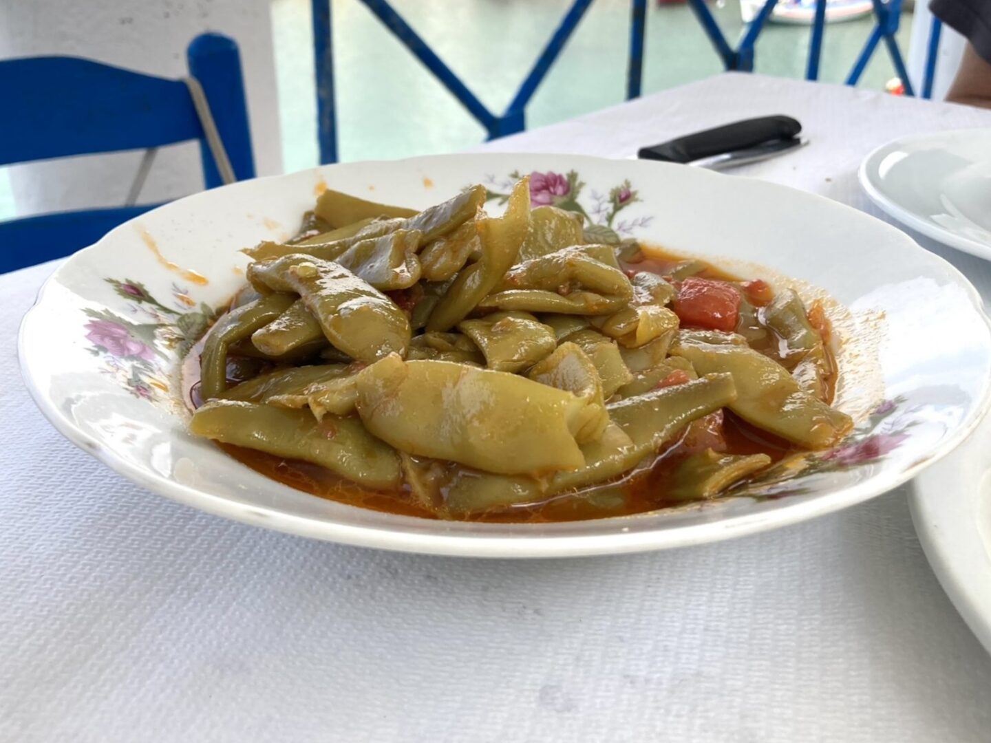 vegan in Greece - Fasolakia in Tomatensauce auf einem Teller mit Blumen